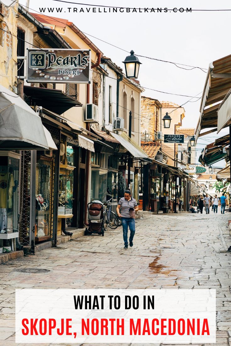 Stone pedestrian street in Skopje Old Bazaar lined with shops and locals walking under street lamps and shop signs.